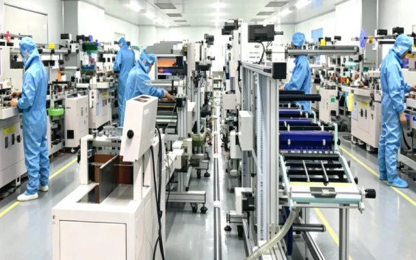 Operators in blue cleanroom suits at die-cut presses in the Dongguan plant